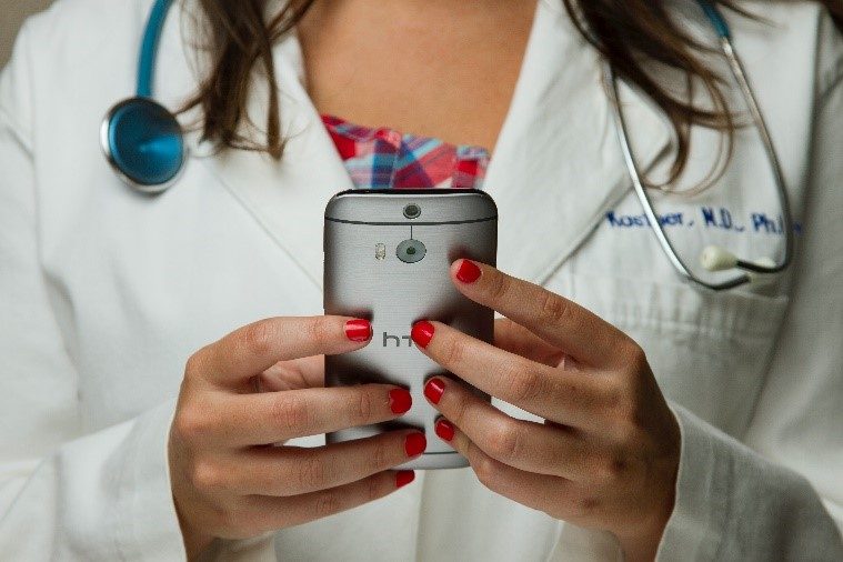 BIld mit einer Ärztin, die auf ein Handy schaut