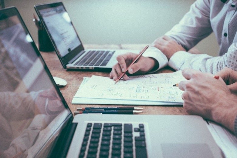 SAFE1 2 Laptops und eine Hand, die etwas auf einen Zettel schreibt