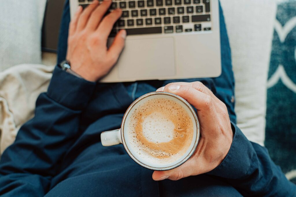 Bild von einer Person mit Kaffee und Laptop